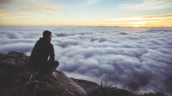 Innere Führung: ein Mann sitzt auf einem Felsen über einem Wolkenmeer