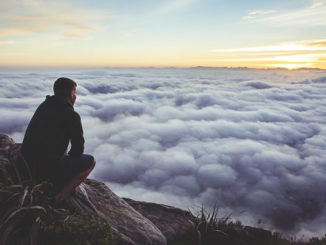 Innere Führung: ein Mann sitzt auf einem Felsen über einem Wolkenmeer