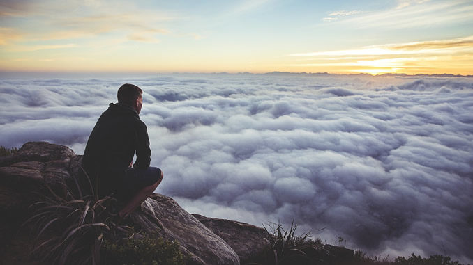 Innere Führung: ein Mann sitzt auf einem Felsen über einem Wolkenmeer