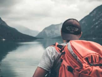 mann mit rucksack am see auf selbstfindungsreise