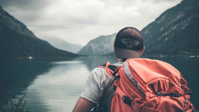mann mit rucksack am see auf selbstfindungsreise