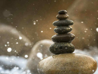 Ein Stapel flacher Steine am Wasser als Symbol für Balance