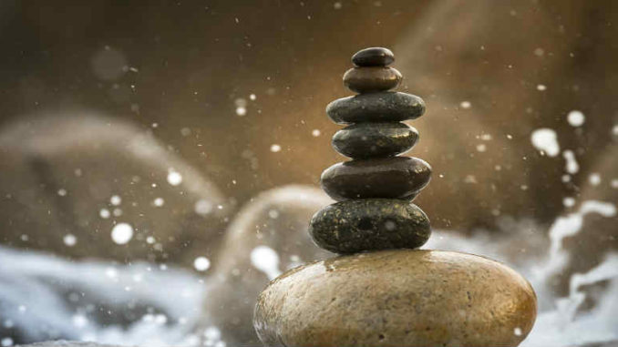 Ein Stapel flacher Steine am Wasser als Symbol für Balance