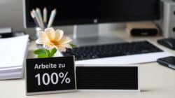 Arbeitsumfeld im Wassermannzeitalter: Schreibtisch mit Bildschirm, Blume und einem Schild zur Arbeitsleistung Arbeitsumfeld im Wassermannzeitalter: Schreibtisch mit Bildschirm, Blume und einem Schild zur Arbeitsleistung