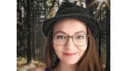 Porträt von Anja Müller mit Brille und Hut im Wald