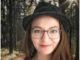 Porträt von Anja Müller mit Brille und Hut im Wald
