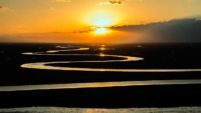 Sonnenaufgang über einem Fluss in der Prärie