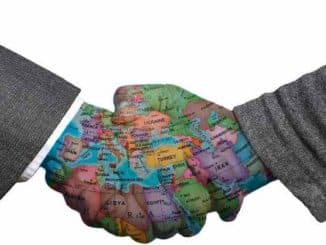 Händedruck mit einer Weltkarte als Symbol für Frieden und internationale Verständigung