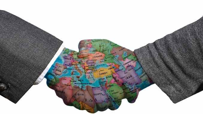 Händedruck mit einer Weltkarte als Symbol für Frieden und internationale Verständigung