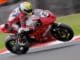 Motorradrennfahrer auf einem roten Superbike auf der Rennstrecke