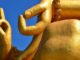 Mudras an einer goldfarbenen Buddha-Statue vor blauem Himmel