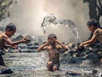 Naturreligionen: Symbolfoto mit Kindern, die im Wasser spielen