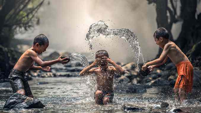 Naturreligionen: Symbolfoto mit Kindern, die im Wasser spielen