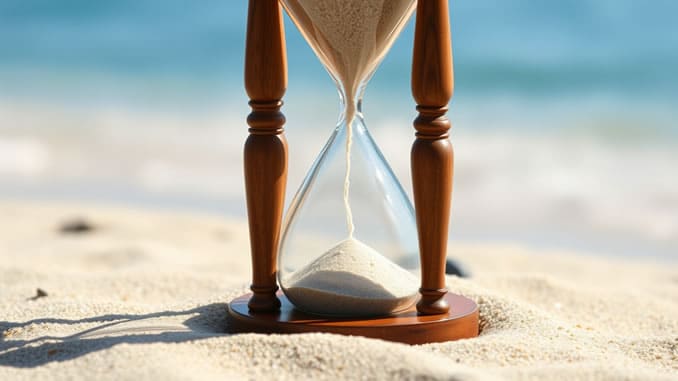 eine Sanduhr steht am Strand im Sand