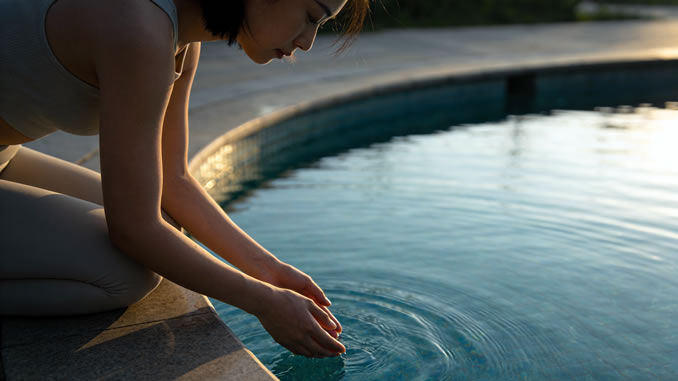 eine Frau schöpft Wasser aus einem Becken