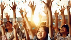 Zum Thema Indigo Mensch: KI-Illustration von Kindern mit erhobenen Händen und Konfetti