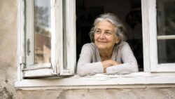 Betreuungskraft zu Hause Ältere Frau am verwitterten Fenster