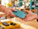 ein gebrauchtes Smartphone wird von einer Hand zur anderen weitergegeben